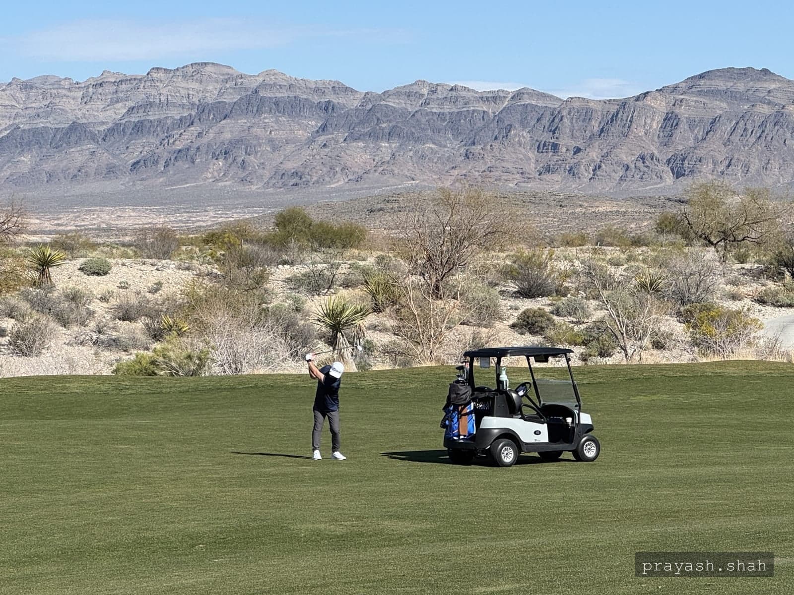 Golfing on a desert course beneath a mountain range